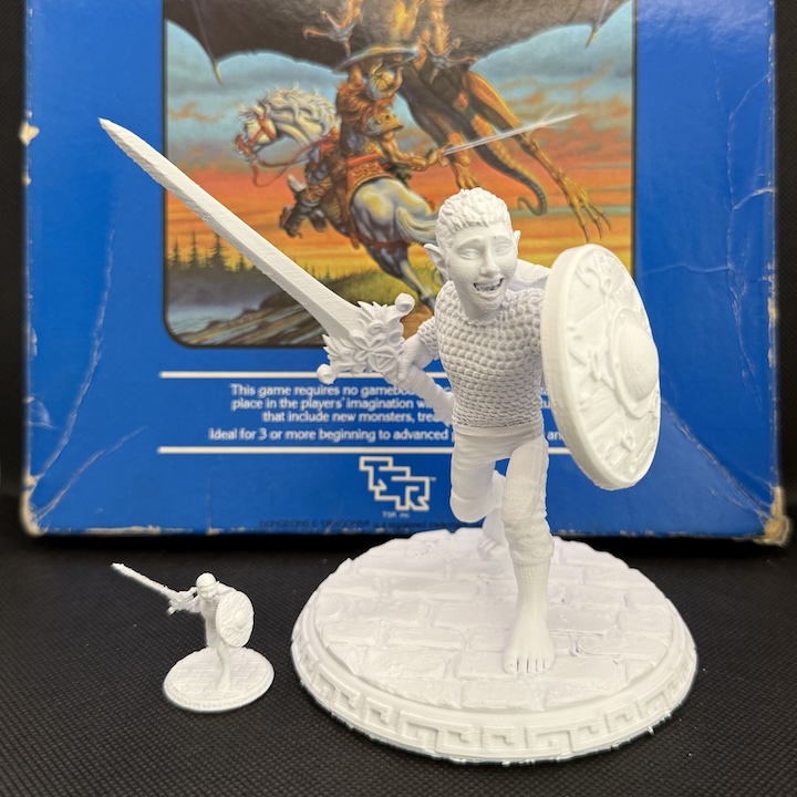 A 3D printed 25mm miniature and a 400% scaled up version, in front of the 1983 D&D Expert Set