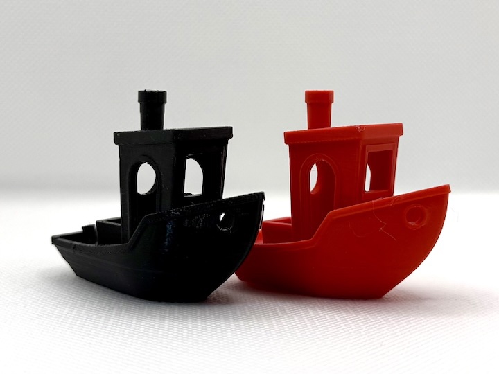 Two 3D printed tugboats, one black and one red.